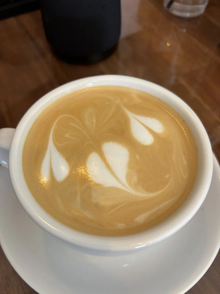 Cappuccino with foam art in a white cup viewed from above.