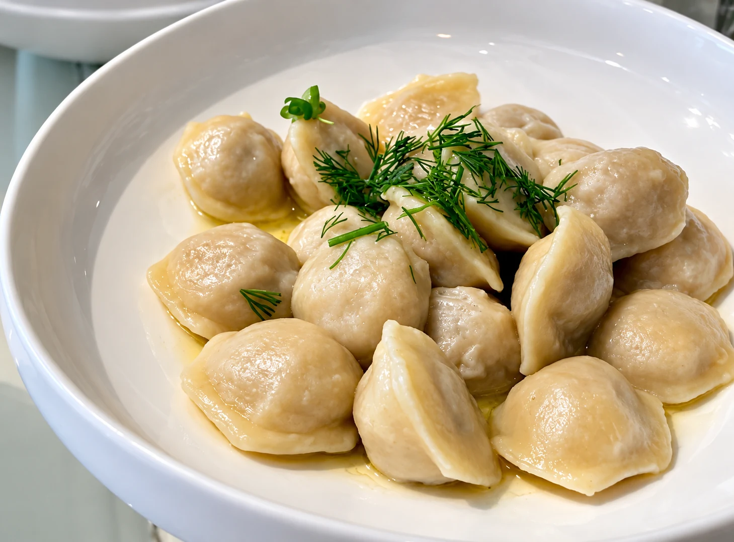 Pelmeni dumplings served with sour cream and dill.