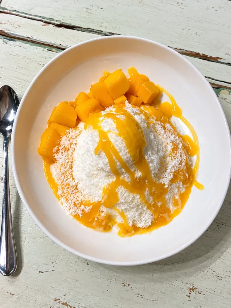 Snowflake ice cream topped with mango sauce and mango pieces.