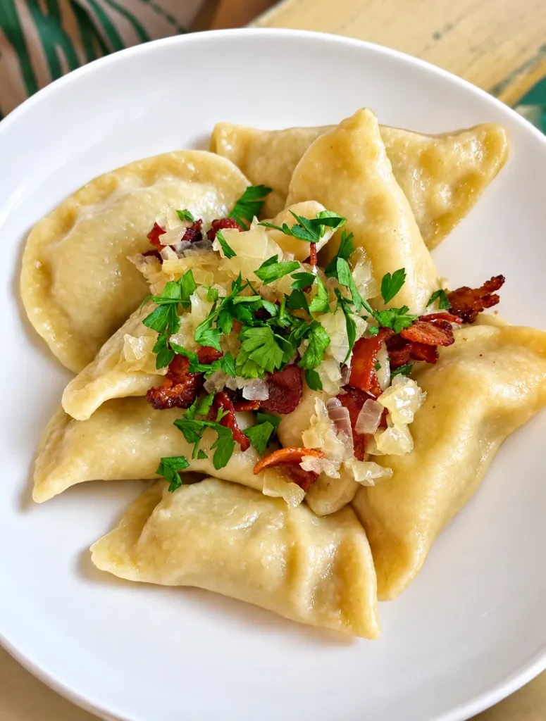 Varenyky dumplings topped with bacon, onions, and fresh herbs.